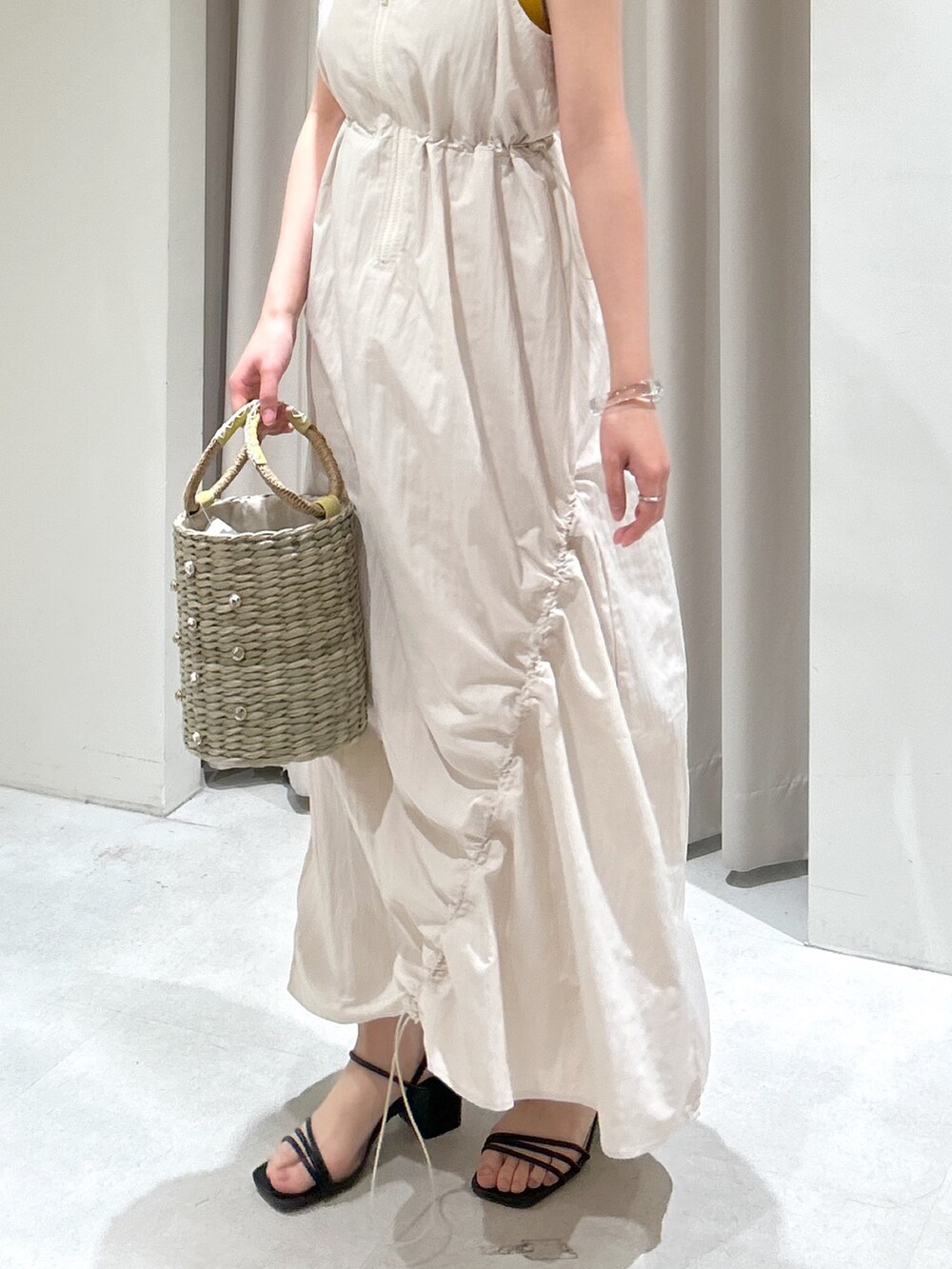 イエロー系のニット/セーター、ホワイト系のワンピースを着用したレディースの春コーディネートの3枚目の写真