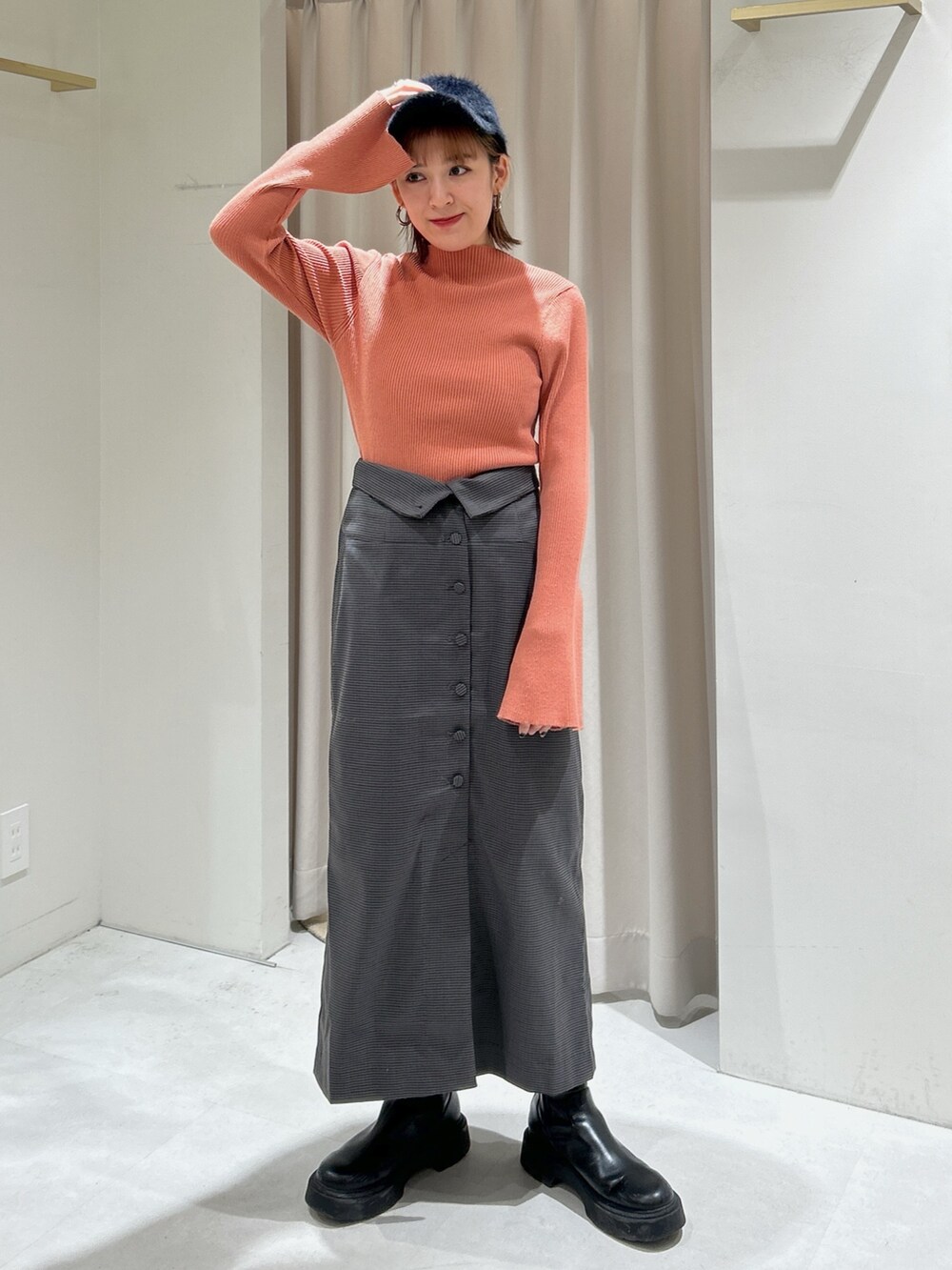 オレンジ系のニット/セーター、グレー系のスカートを着用したレディースの冬コーディネートの3枚目の写真
