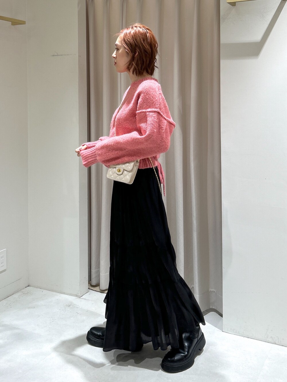 ピンク系のニット/セーター、ブラック系のスカート、ホワイト系のショルダーバッグを着用したレディースの冬コーディネートの3枚目の写真