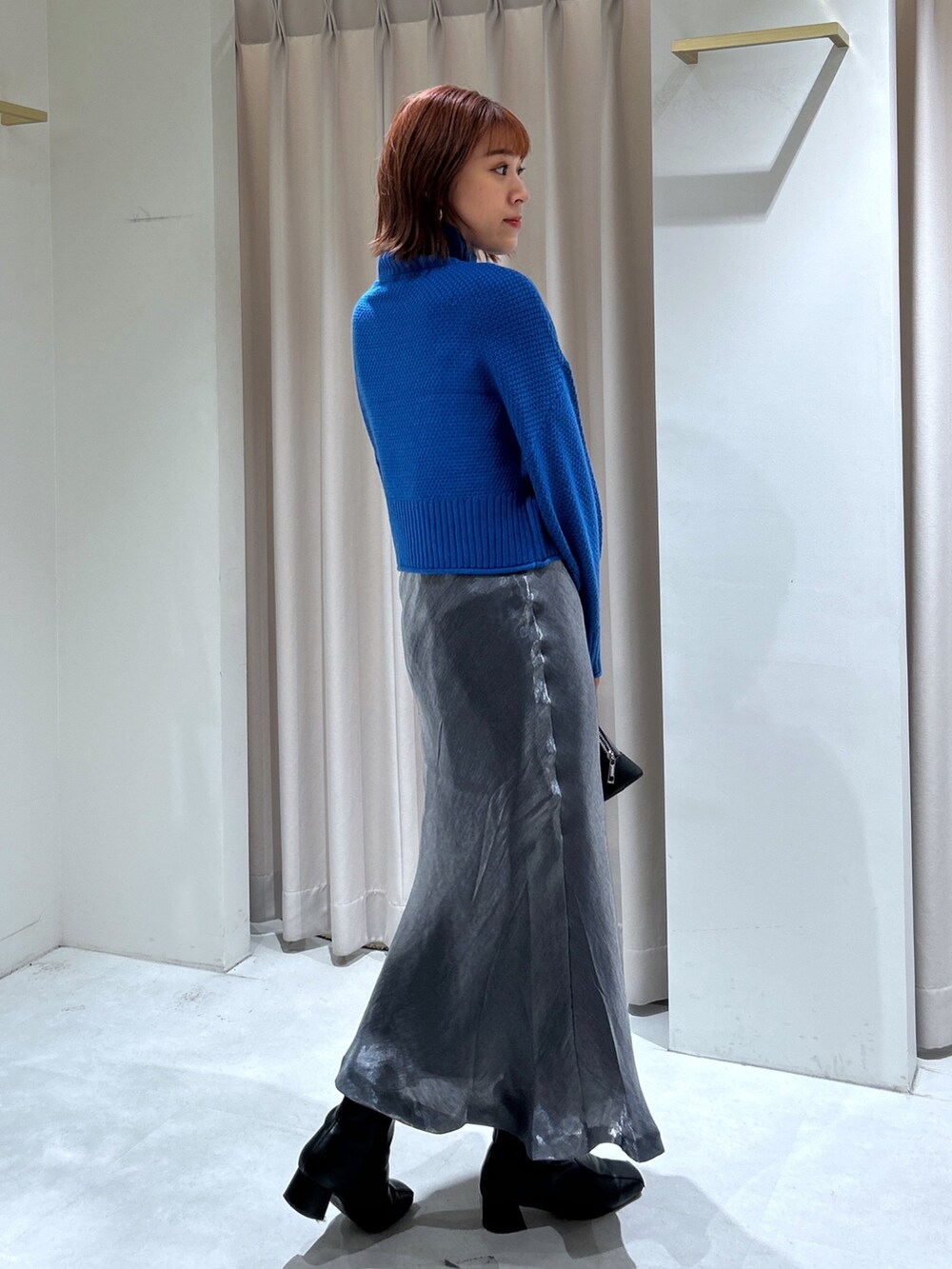 ブルー系のニット/セーター、ブラック系のスカートを着用したレディースの秋コーディネートの3枚目の写真