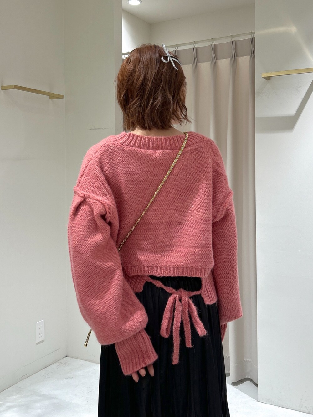 ピンク系のニット/セーター、ブラック系のスカート、ホワイト系のショルダーバッグを着用したレディースの冬コーディネートの5枚目の写真