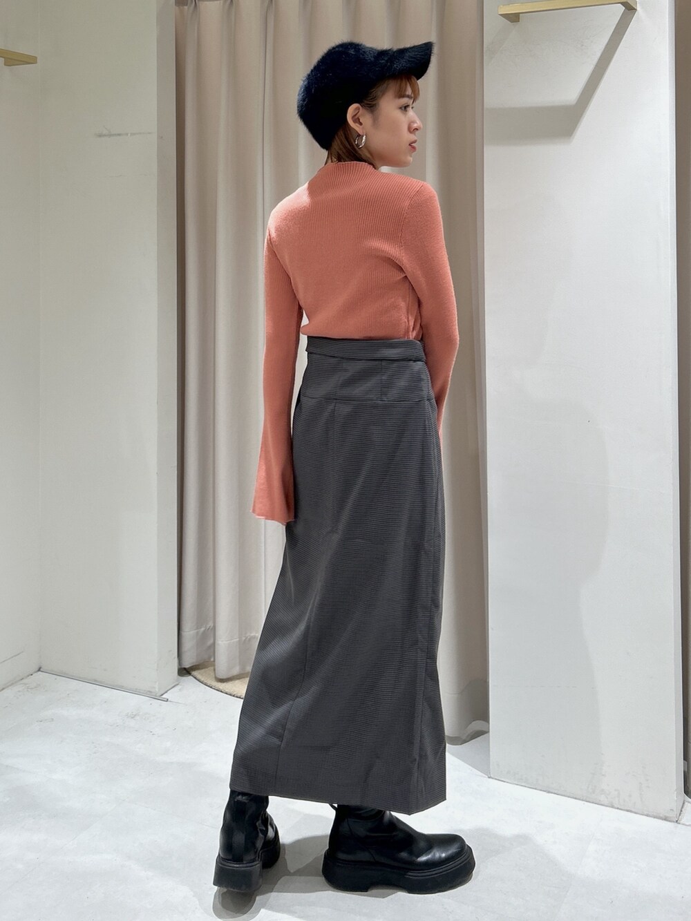 オレンジ系のニット/セーター、グレー系のスカートを着用したレディースの冬コーディネートの2枚目の写真