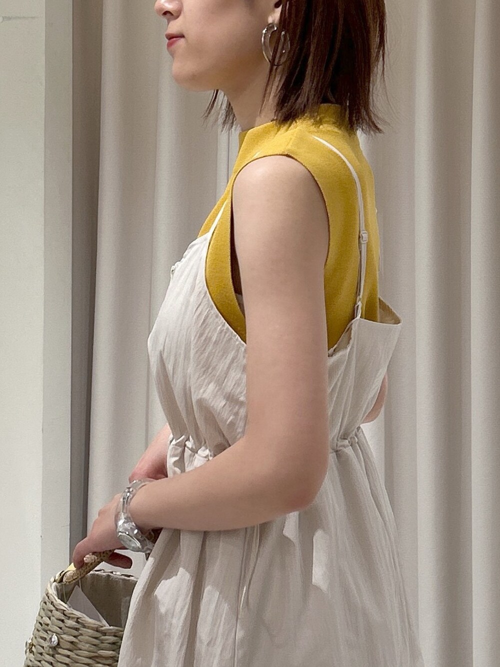 イエロー系のニット/セーター、ホワイト系のワンピースを着用したレディースの春コーディネートの4枚目の写真