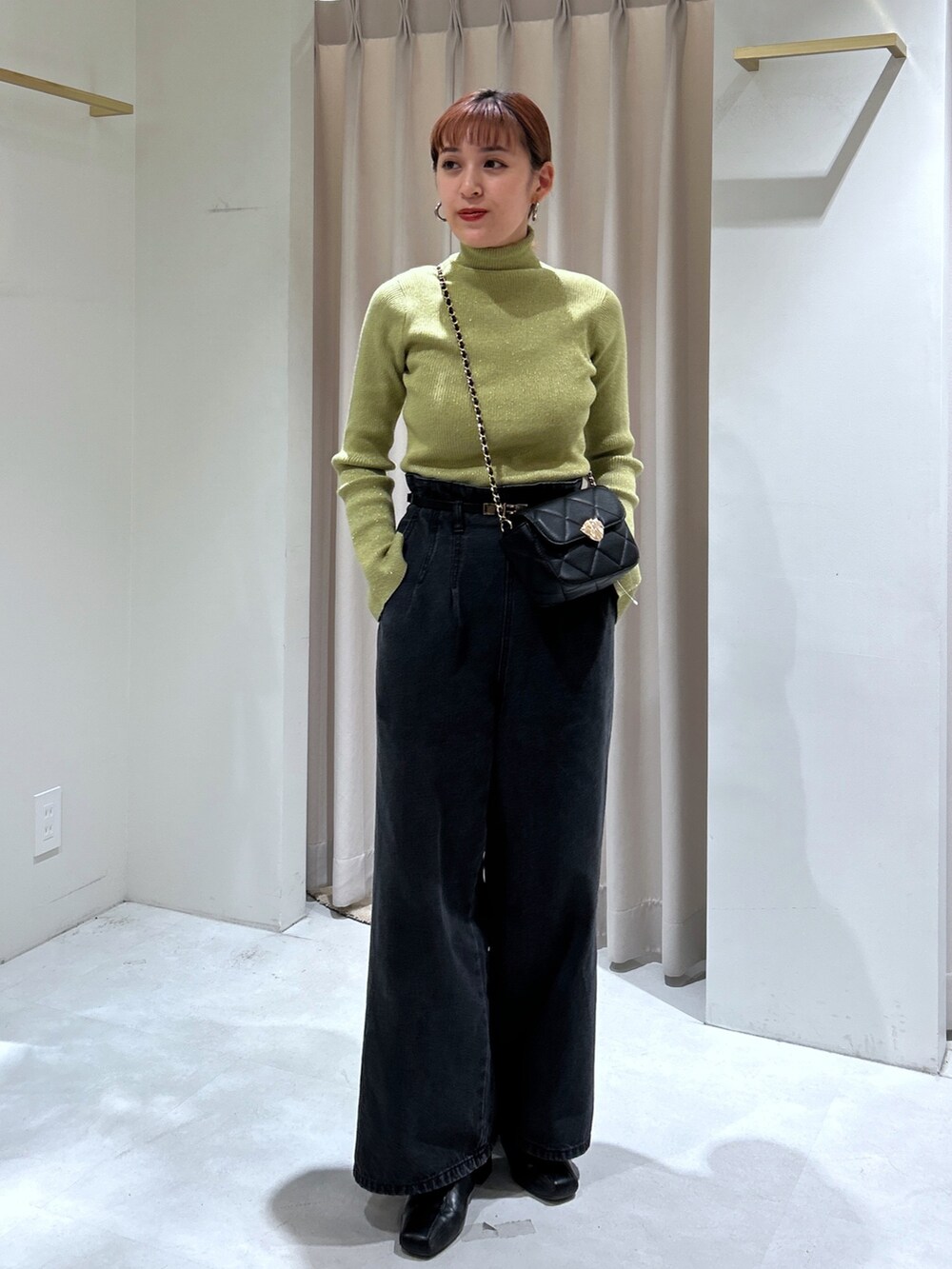 ブラック系のデニムパンツ、グリーン系のニット/セーターを着用したレディースの秋コーディネートの2枚目の写真