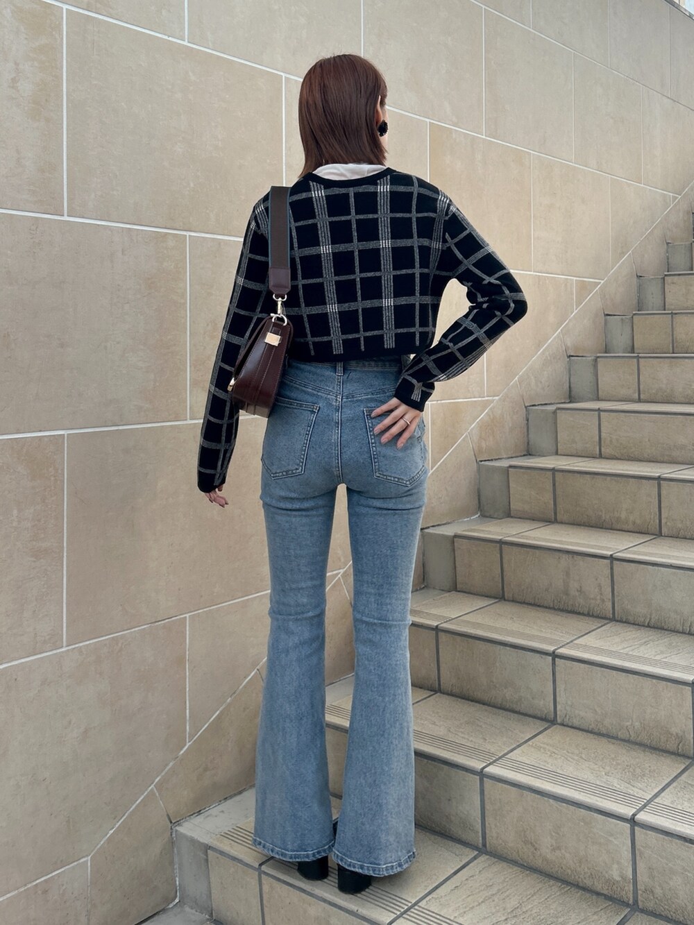 ブラウン系のショルダーバッグ、ブルー系のデニムパンツ、ブラック系のニット/セーターを着用したレディースの冬コーディネートの4枚目の写真