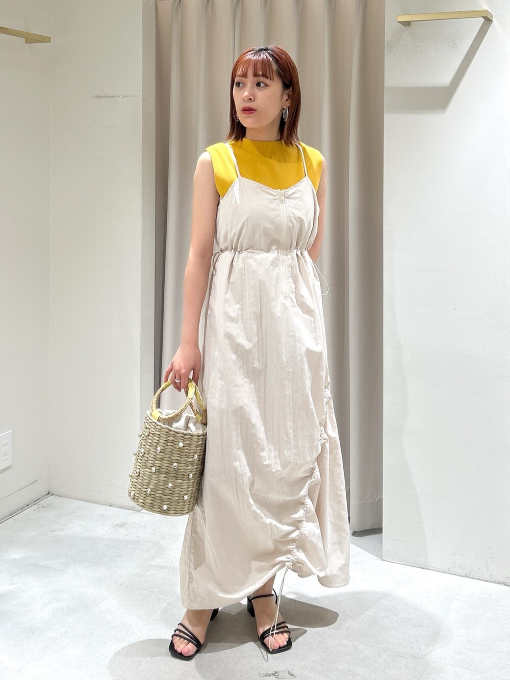 イエロー系のニット/セーター、ホワイト系のワンピースを着用したレディースの春コーディネートの2枚目の写真