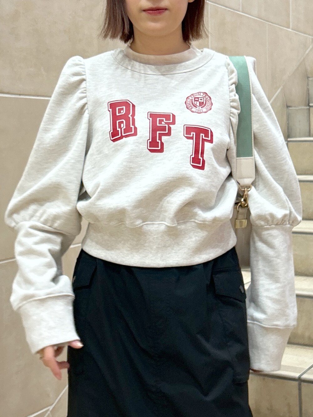 ホワイト系のスウェット、ブラック系のスカートを着用したレディースの春コーディネートの2枚目の写真