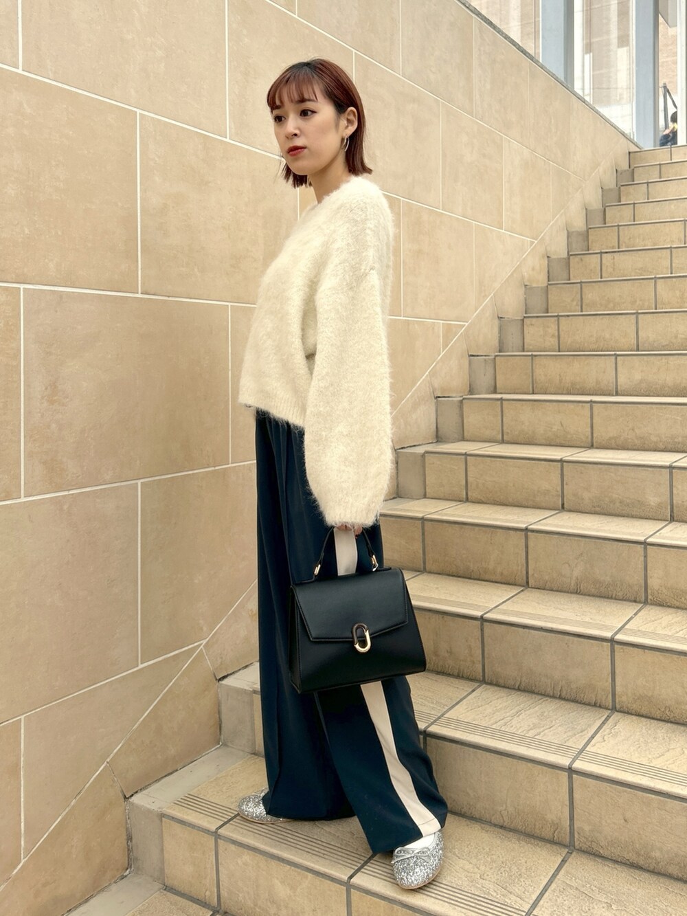 ホワイト系のニット/セーター、グレー系のその他パンツを着用したレディースの冬コーディネートの2枚目の写真