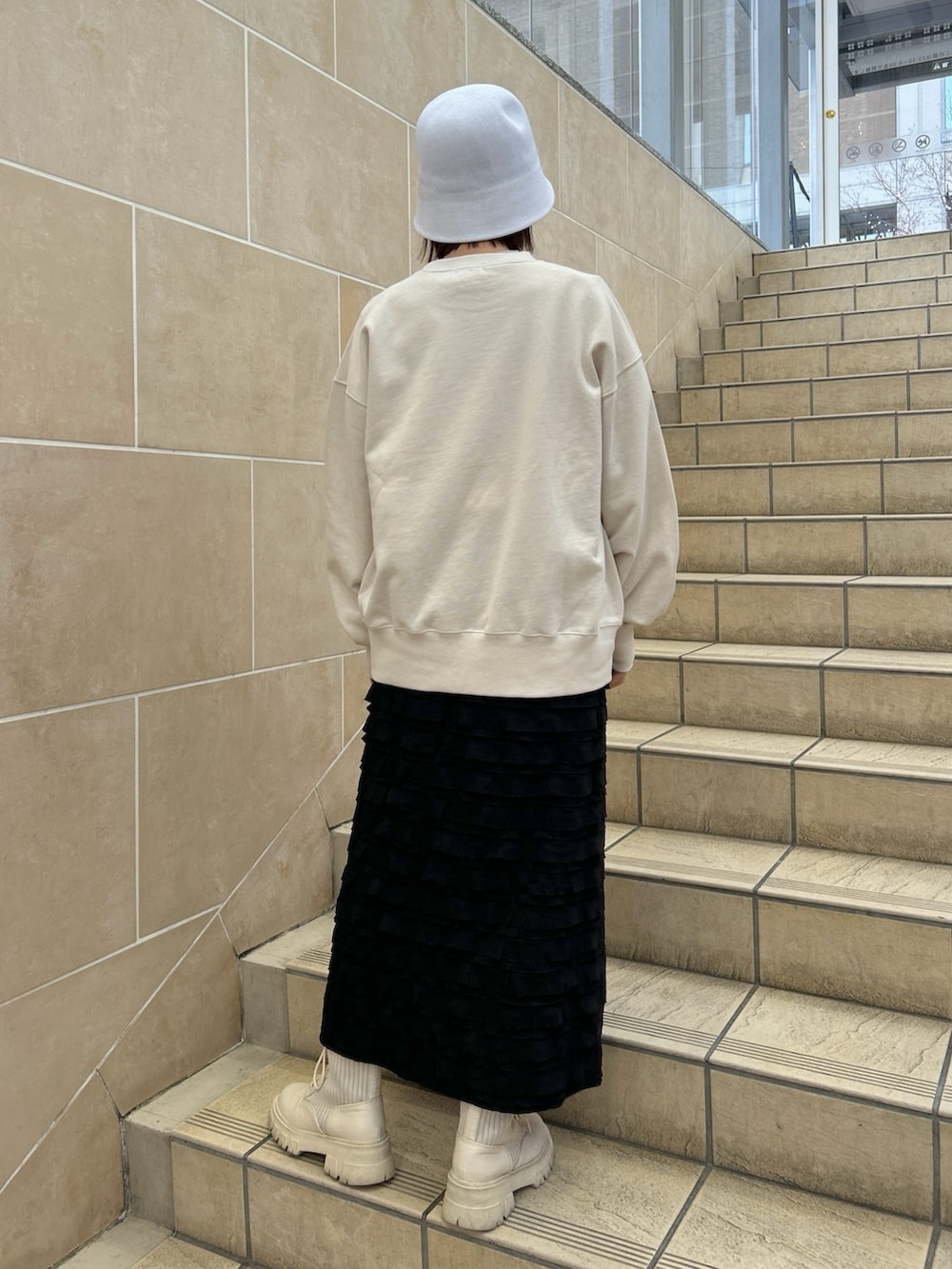 ホワイト系のスウェット、ブラック系のスカートを着用したレディースの春コーディネートの2枚目の写真