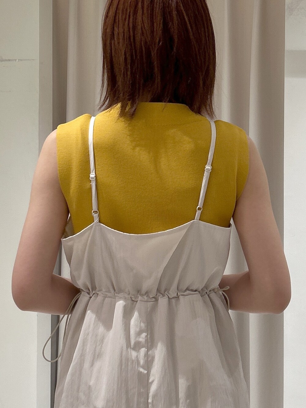 イエロー系のニット/セーター、ホワイト系のワンピースを着用したレディースの春コーディネートの5枚目の写真