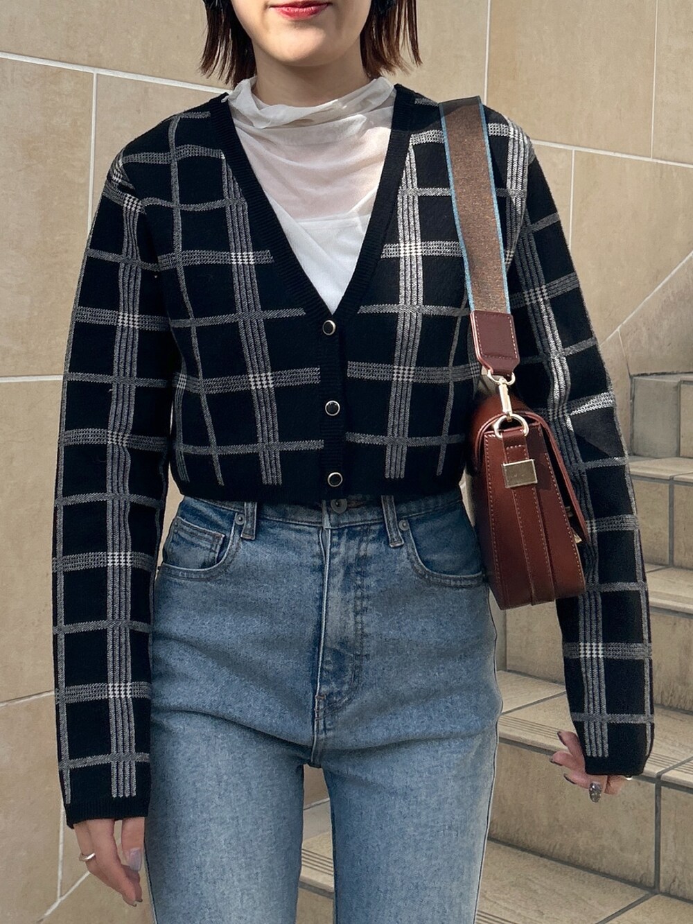 ブラウン系のショルダーバッグ、ブルー系のデニムパンツ、ブラック系のニット/セーターを着用したレディースの冬コーディネートの6枚目の写真