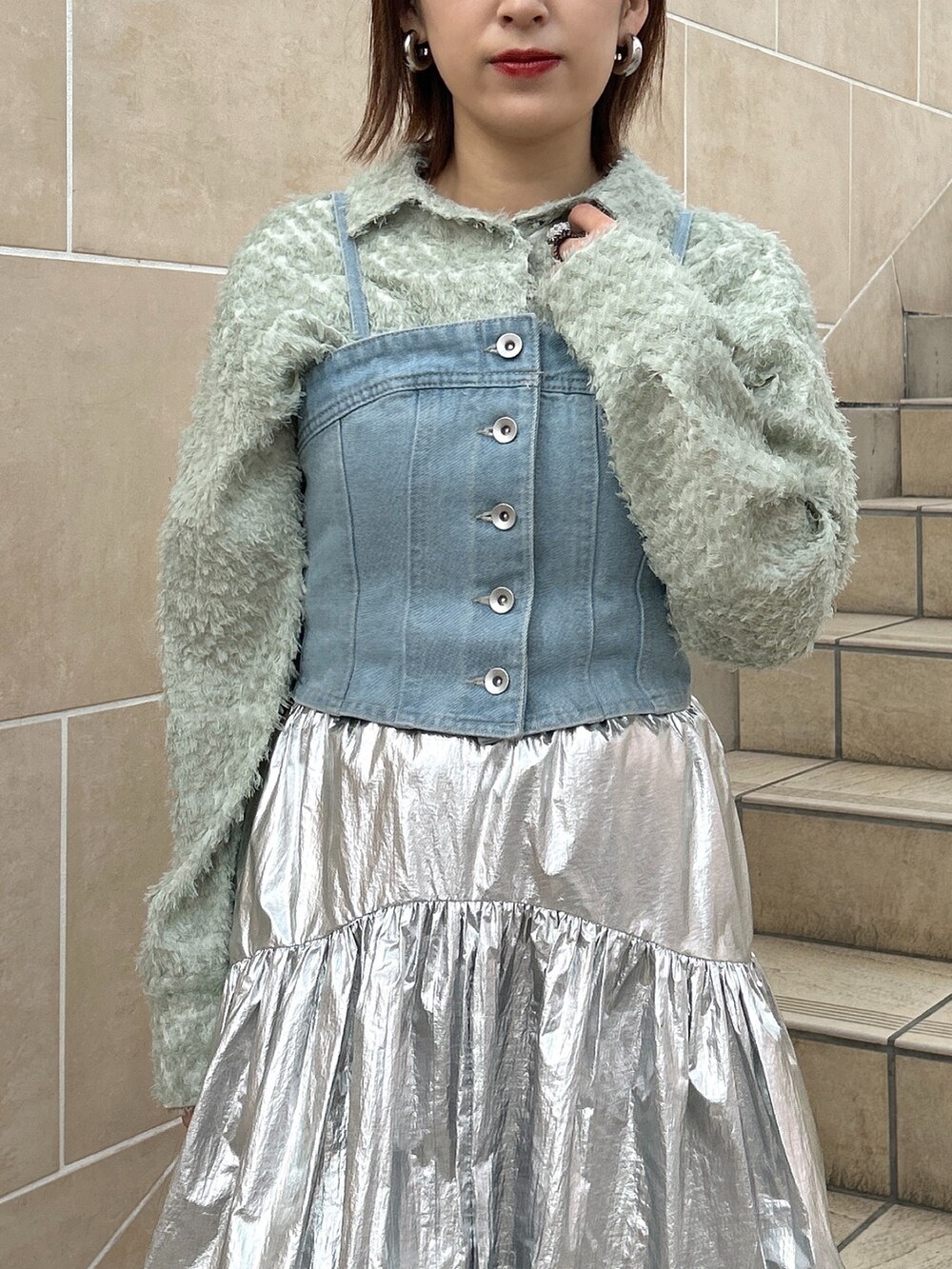 ブルー系のベスト、グリーン系のシャツ/ブラウス、シルバー系のスカートを着用したレディースの春コーディネートの3枚目の写真