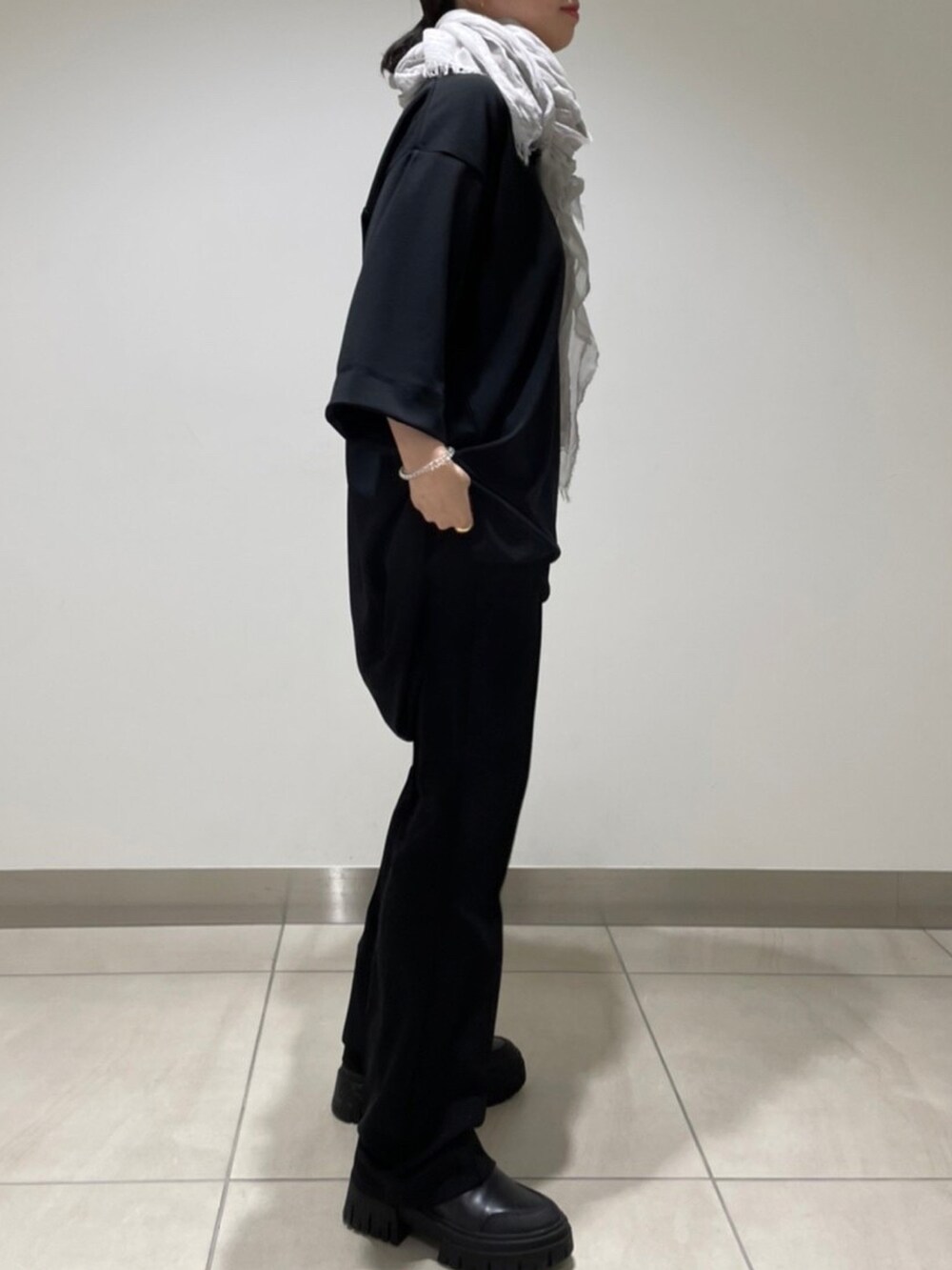 ブラック系のパンツ、ブラック系のTシャツ/カットソー、グレー系のストール/ショールを着用したレディースの冬コーディネートの3枚目の写真
