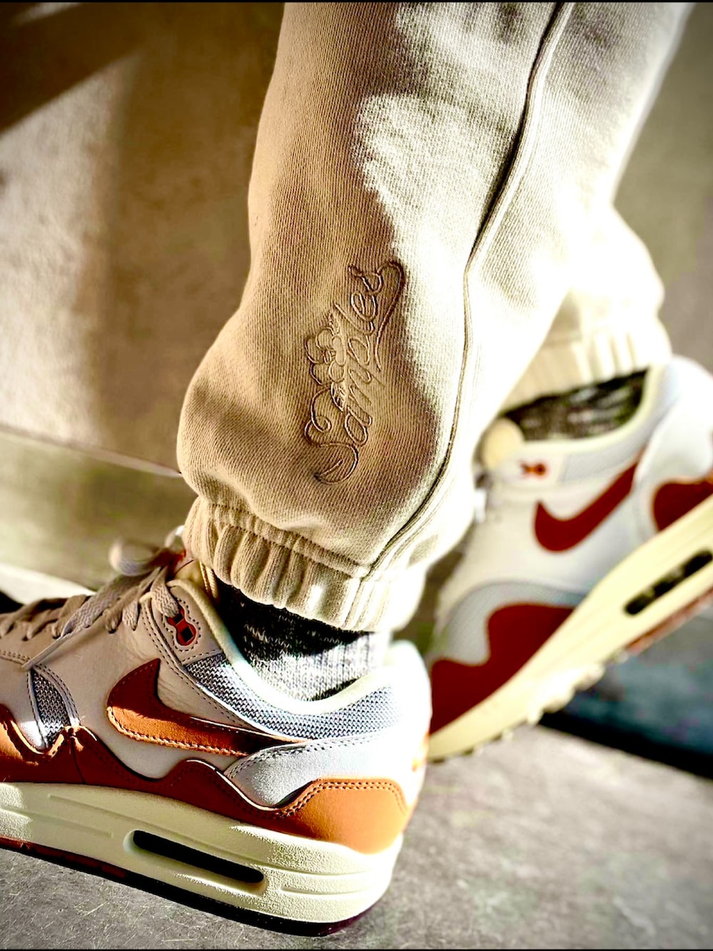 グレー系のトップス、ベージュ系のスウェットパンツ、オレンジ系のスニーカーを着用したメンズの秋コーディネートの2枚目の写真