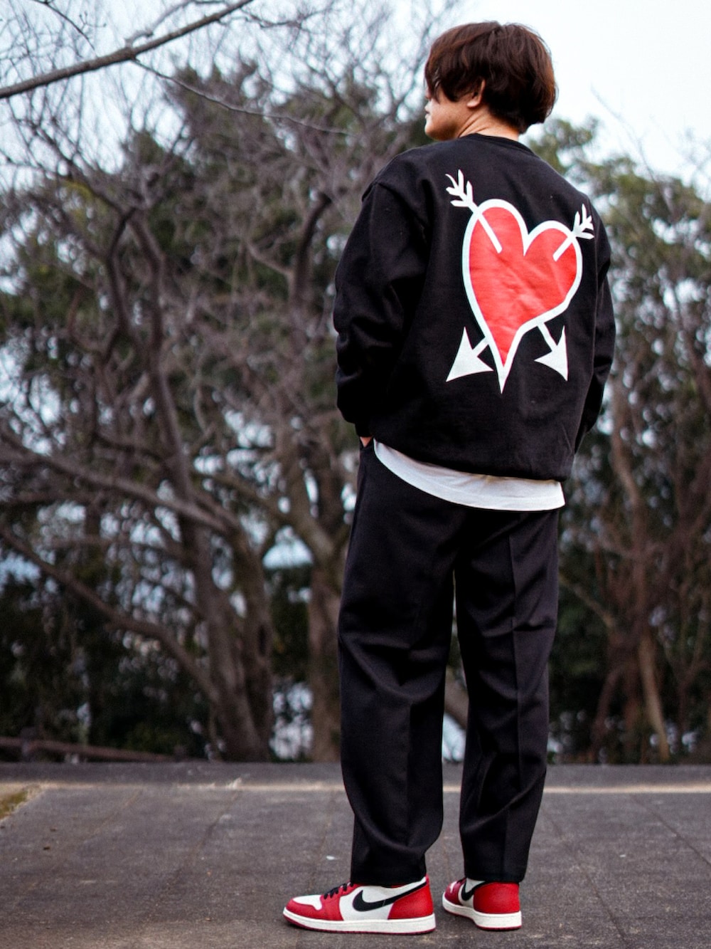 レッド系のスニーカー、ブラック系のスウェット、ブラック系のスラックスを着用したメンズの春コーディネートの2枚目の写真