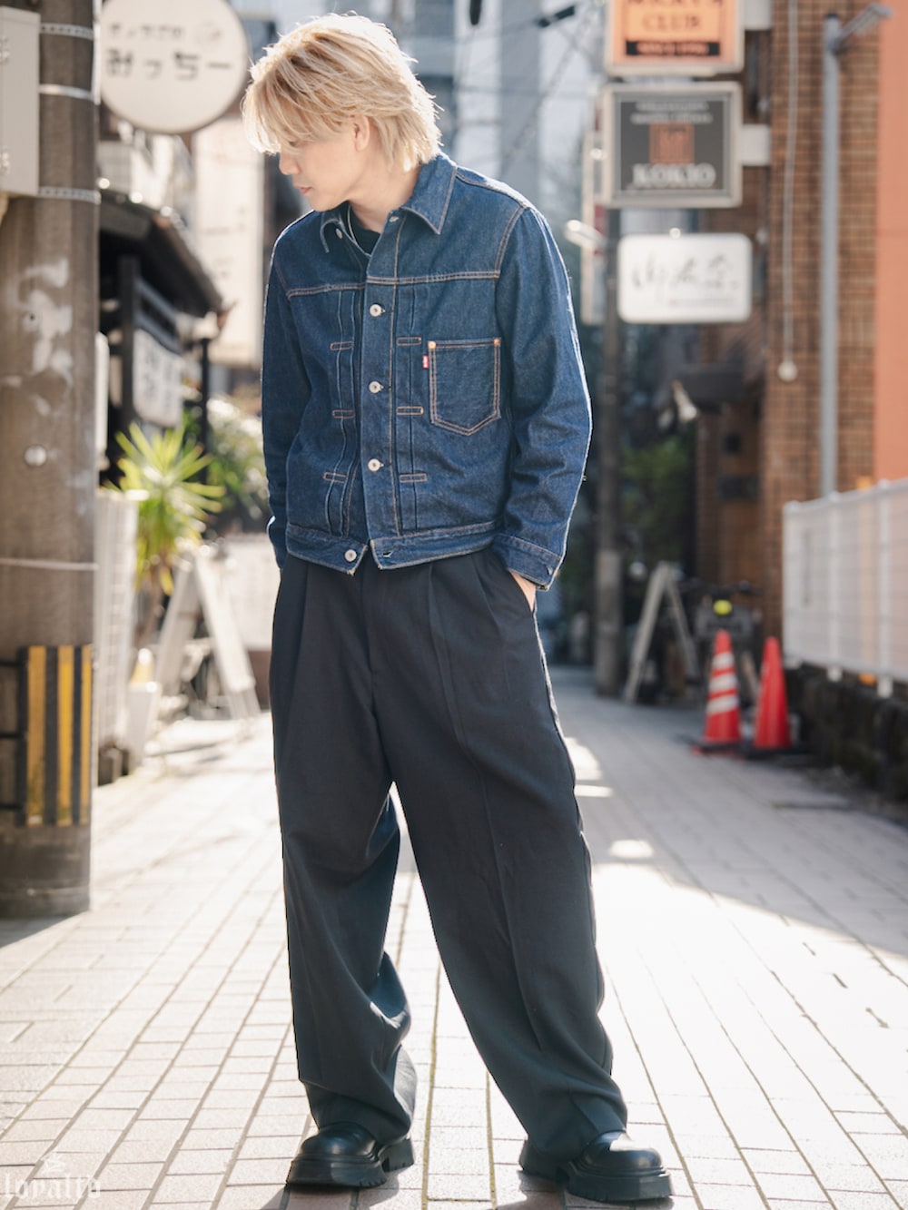 ブルー系のデニムジャケット、ブラック系のスラックス、ブラック系のブーツを着用したメンズの春コーディネートの2枚目の写真