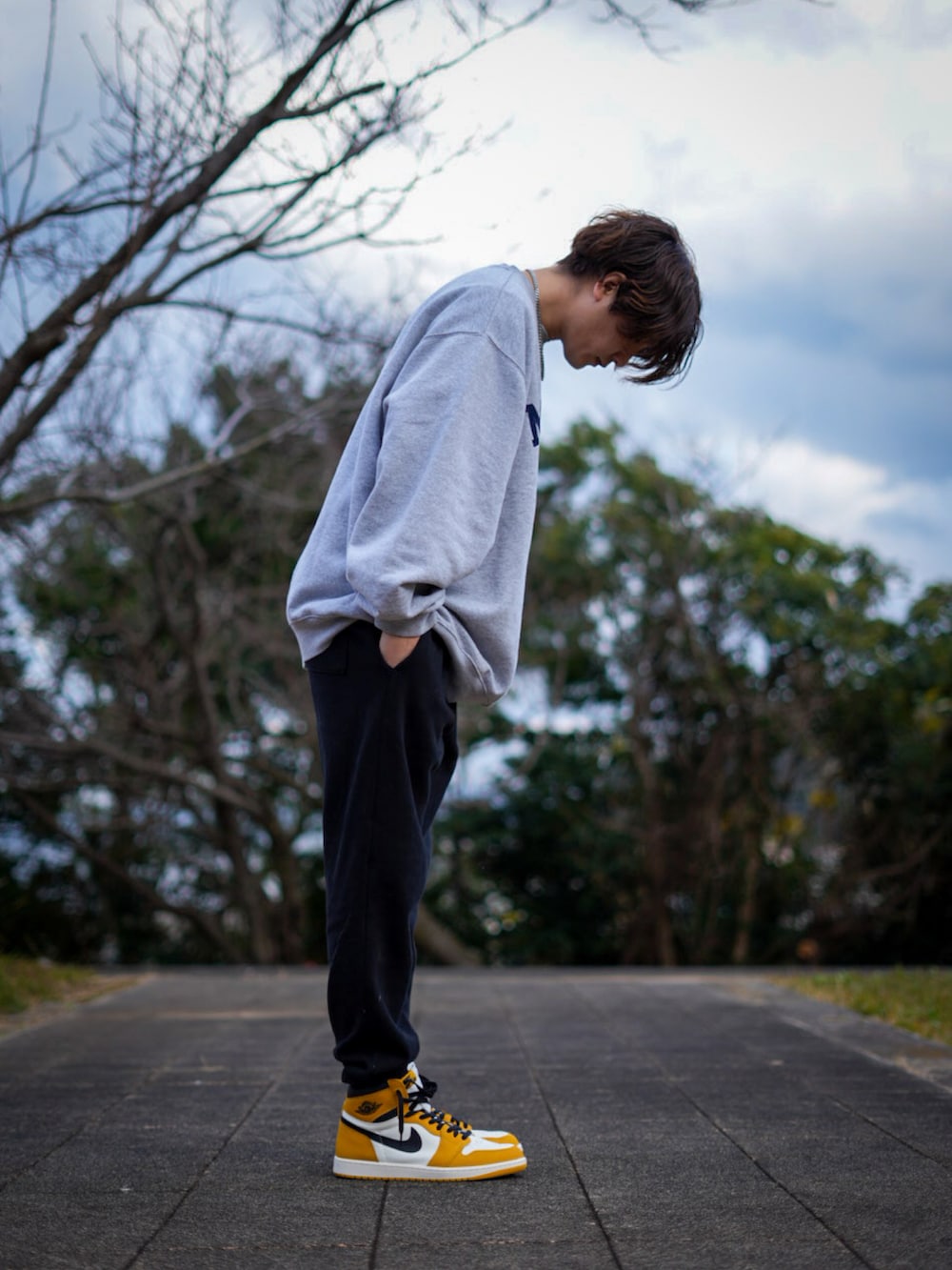 イエロー系のスニーカー、グレー系のスウェット、ブラック系のスウェットパンツを着用したメンズの冬コーディネートの2枚目の写真