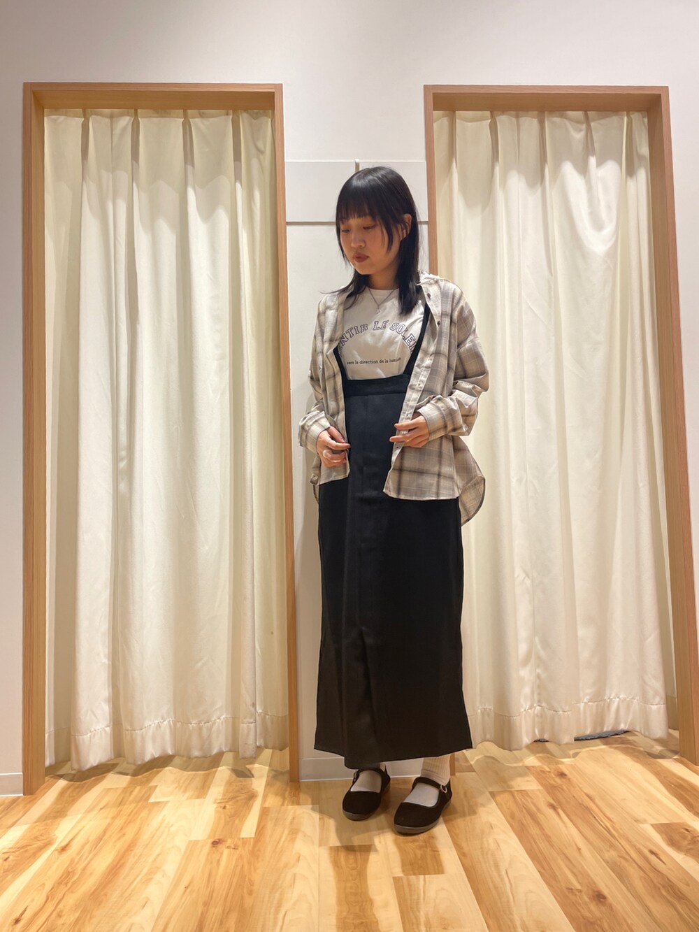 ホワイト系のTシャツ/カットソー、ブラック系のジャンパースカート、ベージュ系のシャツ/ブラウスを着用したレディースの秋コーディネートの3枚目の写真