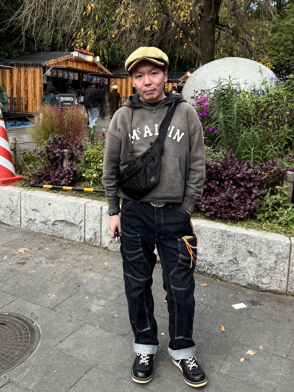 グレー系のパーカー、ブルー系のデニムパンツ、ブラック系のショルダーバッグを着用したメンズの秋コーディネートの2枚目の写真