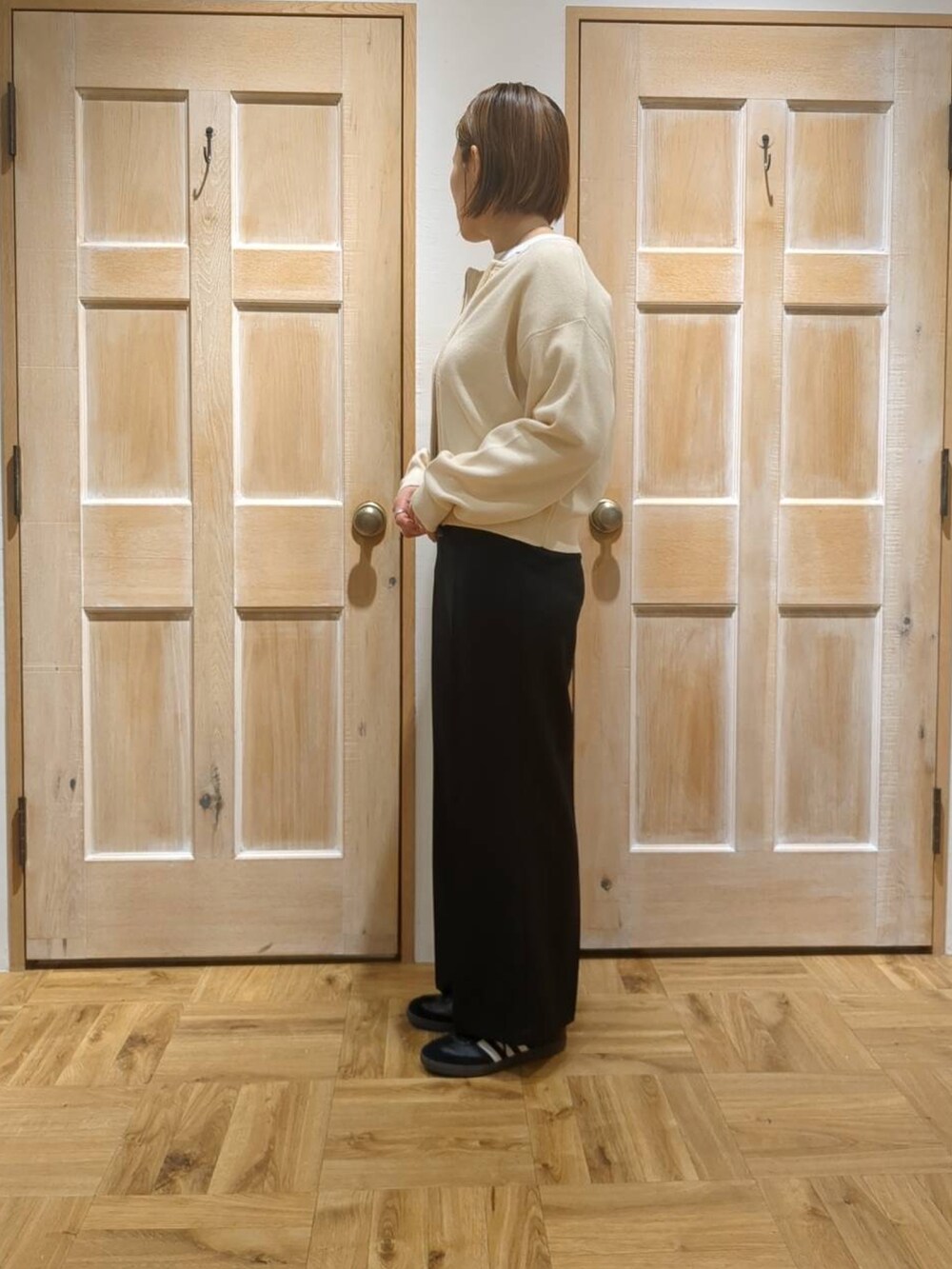 ブラック系のスラックス、ブラック系のTシャツ/カットソー、ホワイト系のカーディガン/ボレロを着用したレディースの冬コーディネートの2枚目の写真