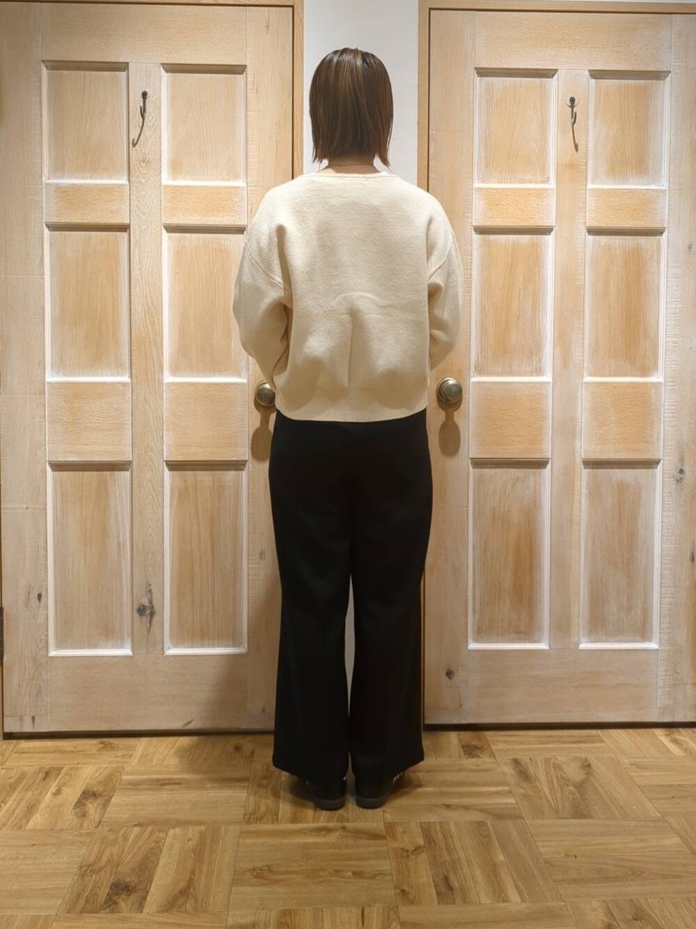 ブラック系のスラックス、ブラック系のTシャツ/カットソー、ホワイト系のカーディガン/ボレロを着用したレディースの冬コーディネートの3枚目の写真