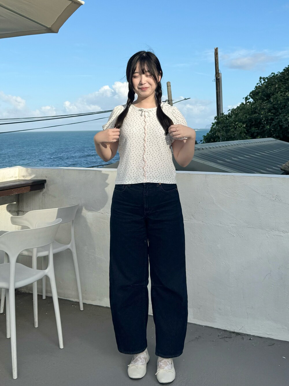 ホワイト系のバレエシューズ、ピンク系のTシャツ/カットソー、ブルー系のデニムパンツを着用したレディースの秋コーディネートの2枚目の写真