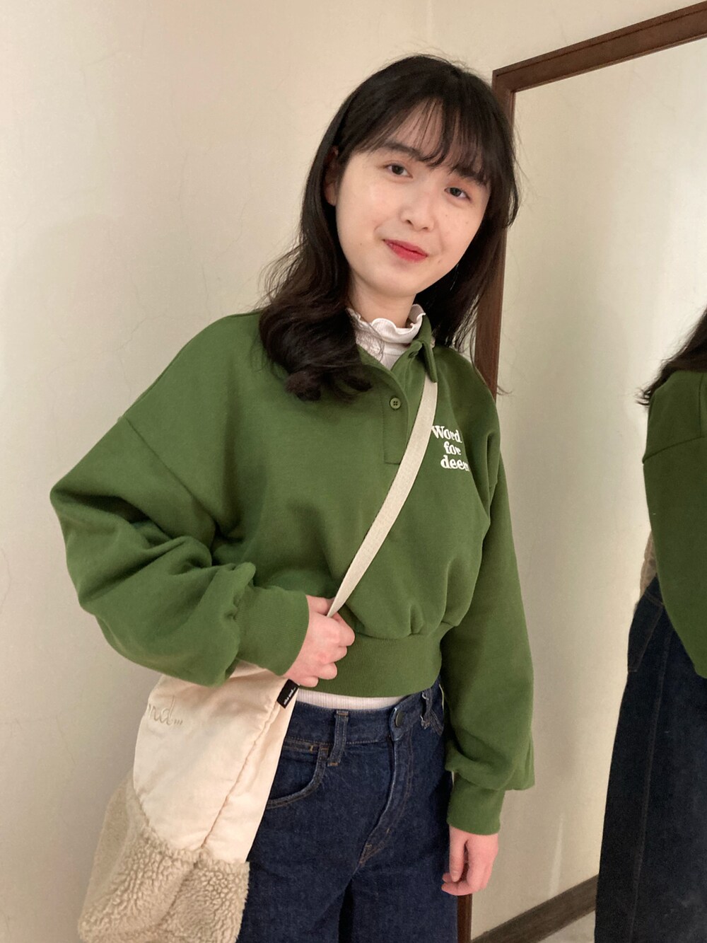 グリーン系のスウェット、ブルー系のデニムパンツ、ホワイト系のシューズを着用したレディースの春コーディネートの3枚目の写真