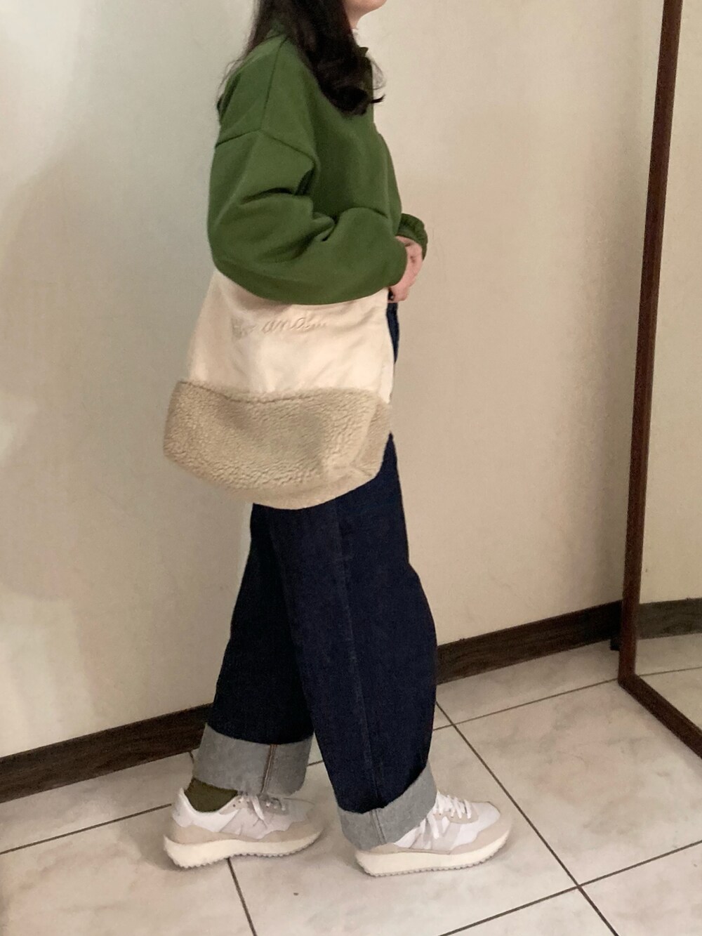 グリーン系のスウェット、ブルー系のデニムパンツ、ホワイト系のシューズを着用したレディースの春コーディネートの2枚目の写真