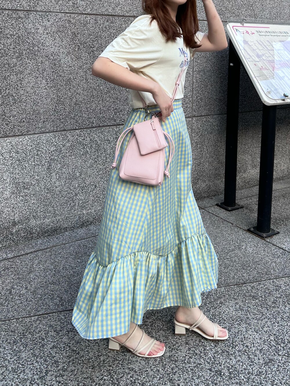 ブルー系のスカート、ピンク系のショルダーバッグ、ベージュ系のTシャツ/カットソーを着用したレディースの春コーディネートの2枚目の写真