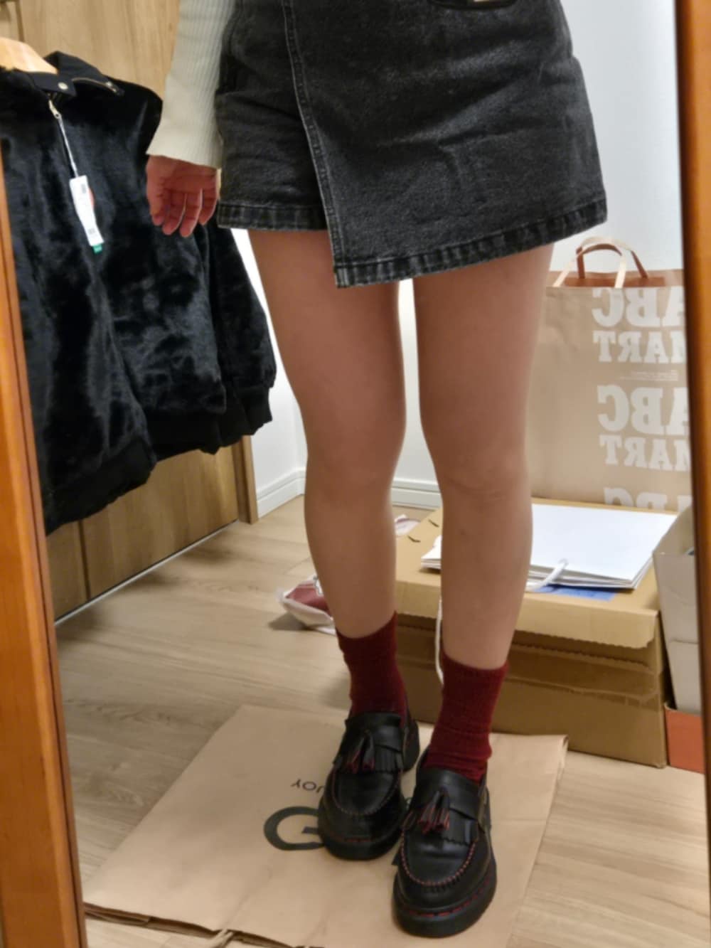 ブラック系のベスト、ブラック系のデニムスカート、ブラック系のローファーを着用したレディースの冬コーディネートの2枚目の写真