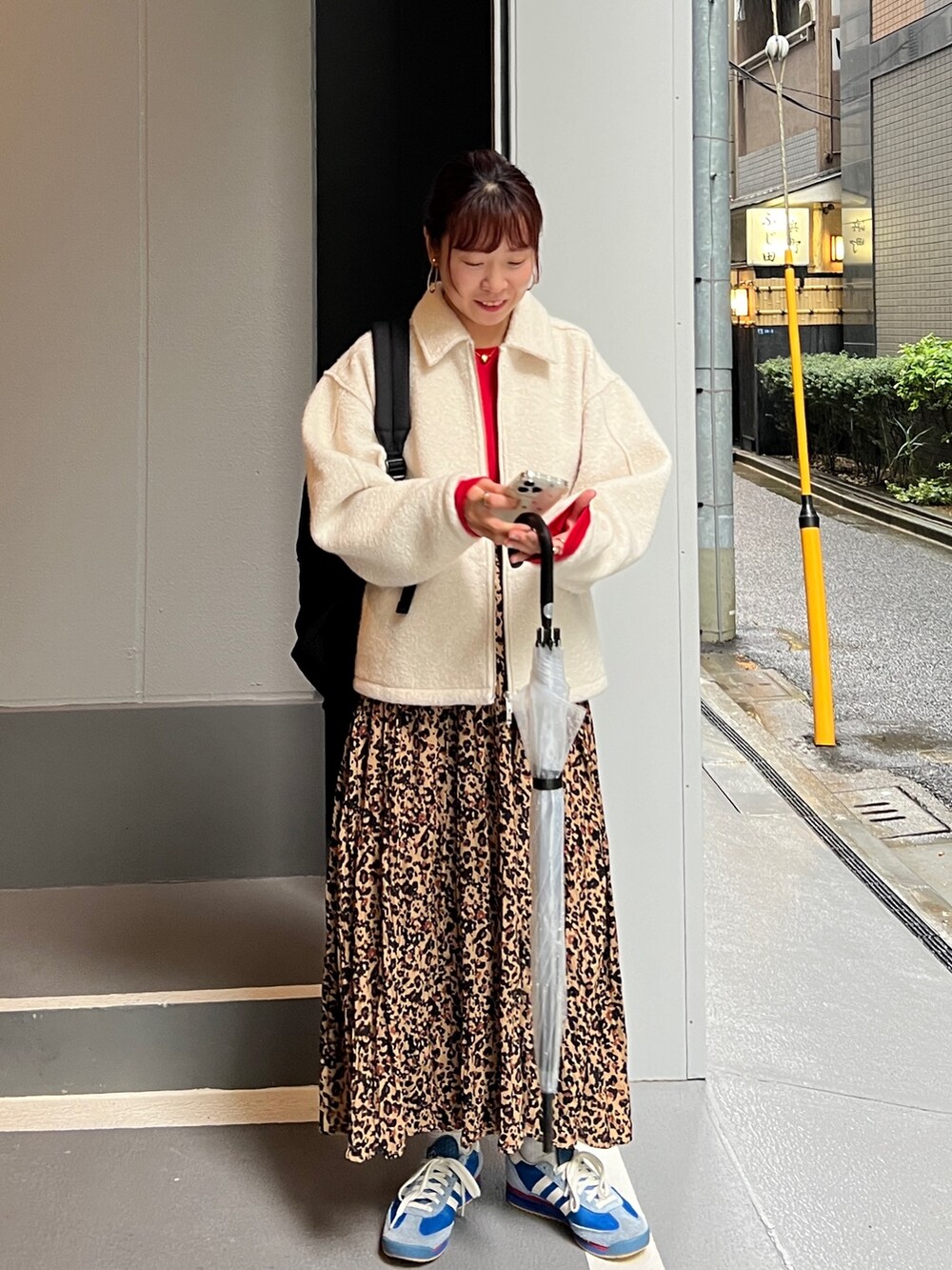 レッド系のTシャツ/カットソー、ホワイト系のブルゾン、ブラウン系のスカートを着用したレディースの秋コーディネートの3枚目の写真