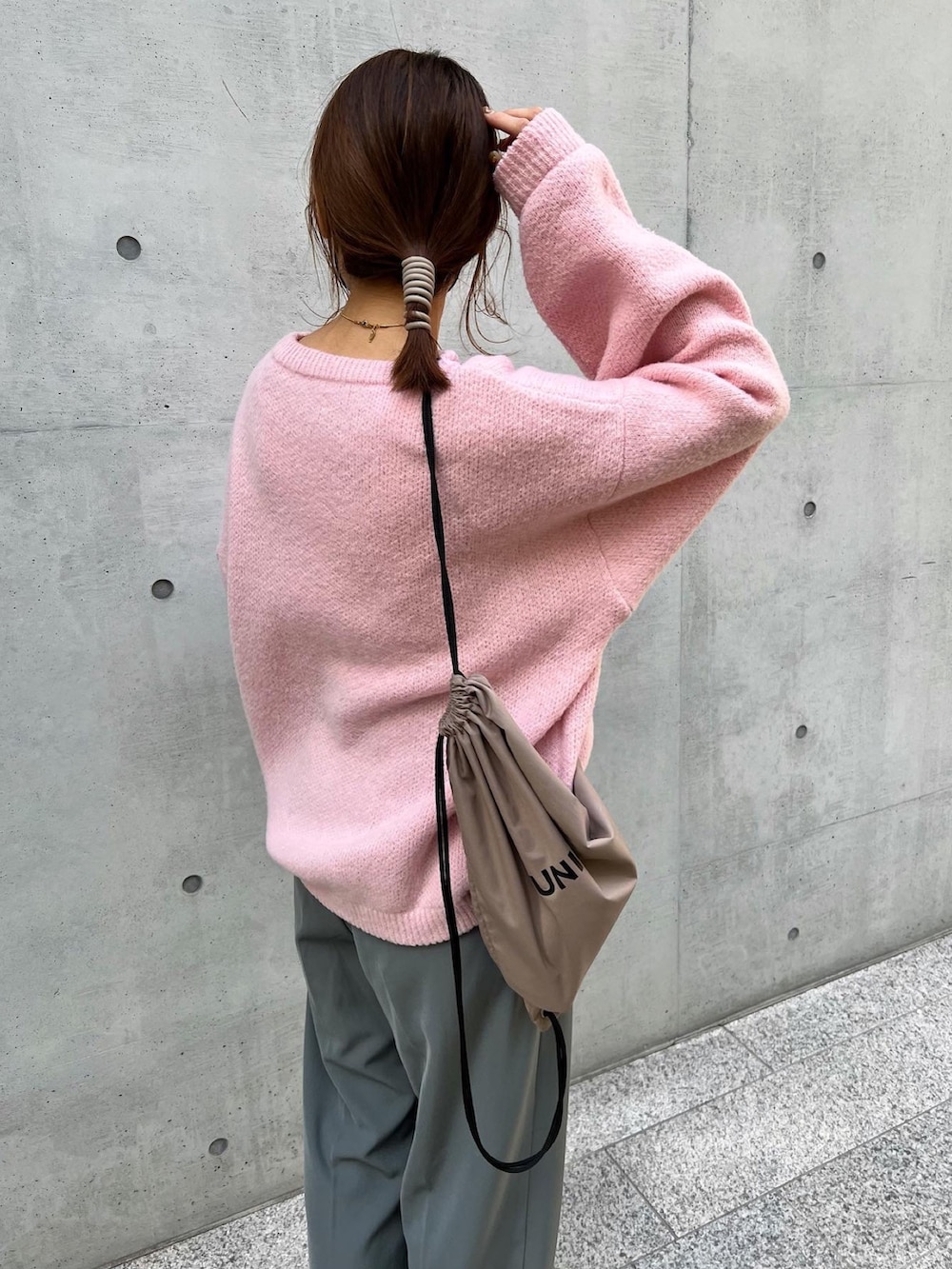 ピンク系のニット/セーター、グレー系のスラックス、ベージュ系のバックパック/リュックを着用したレディースの冬コーディネートの3枚目の写真