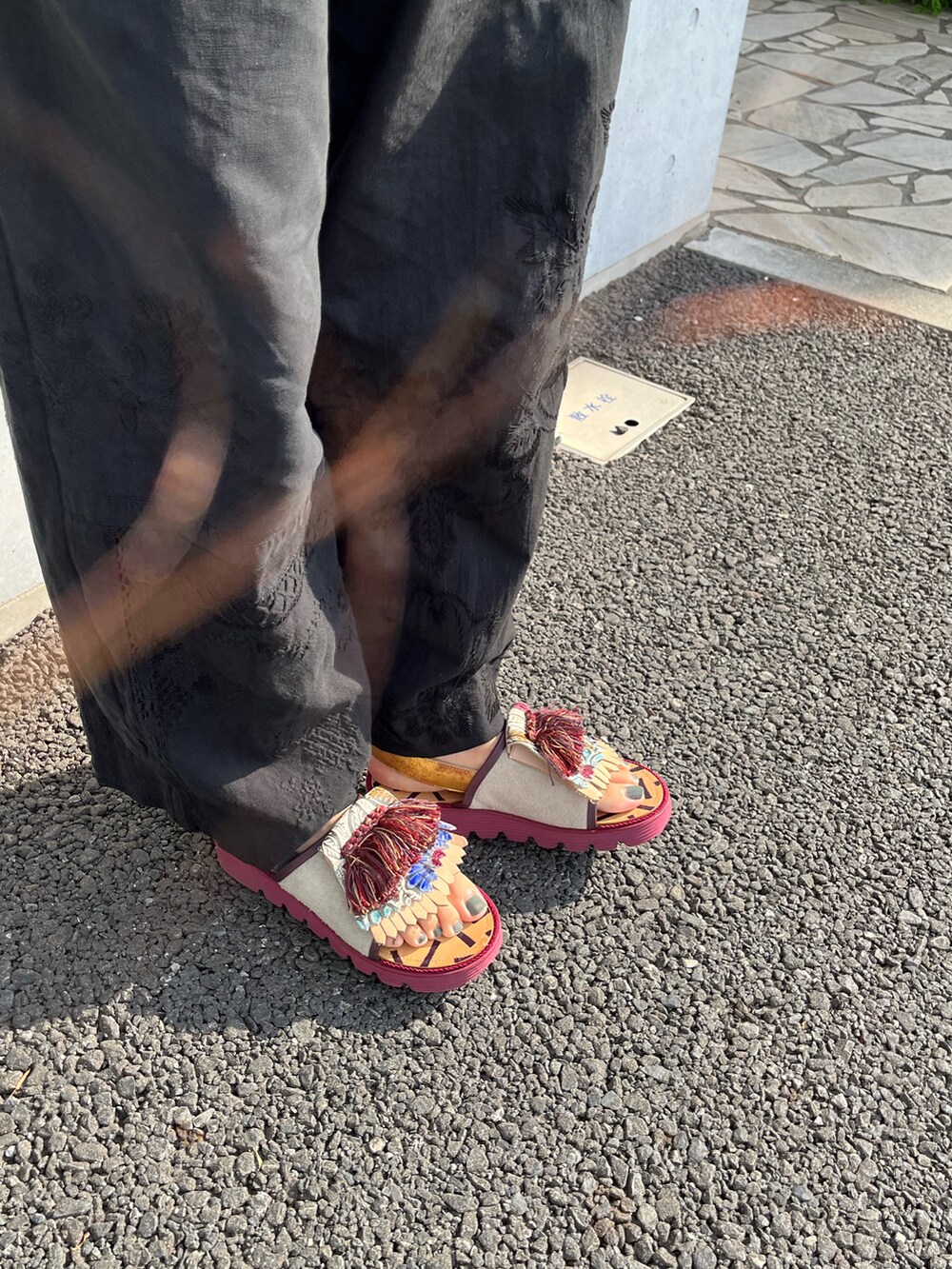 ブラウン系のタンクトップ、ブラック系のパンツ、レッド系のサンダルを着用したレディースの夏コーディネートの4枚目の写真