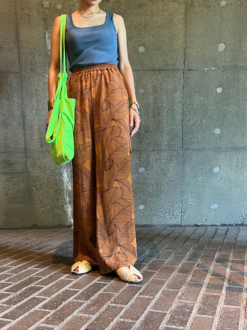 ブルー系のタンクトップ、グリーン系のトートバッグ、ベージュ系のサンダルを着用したレディースの夏コーディネートの2枚目の写真