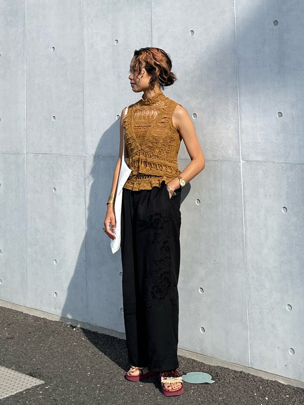 ブラウン系のタンクトップ、ブラック系のパンツ、レッド系のサンダルを着用したレディースの夏コーディネートの2枚目の写真