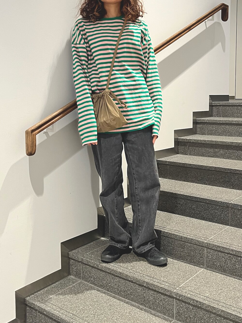 グリーン系のTシャツ/カットソー、ベージュ系のショルダーバッグ、ブラック系のスニーカーを着用したレディースの春コーディネートの3枚目の写真