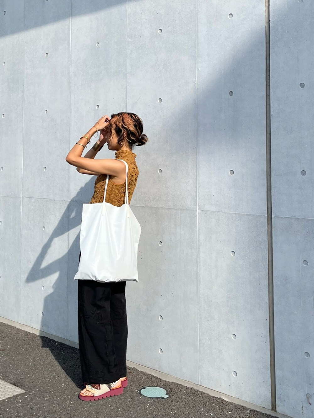 ブラウン系のタンクトップ、ブラック系のパンツ、レッド系のサンダルを着用したレディースの夏コーディネートの3枚目の写真