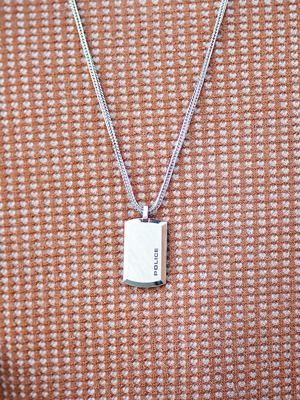 オレンジ系のTシャツ/カットソー、ベージュ系のトレンチコート、ブルー系のデニムパンツを着用したメンズの秋コーディネートの2枚目の写真