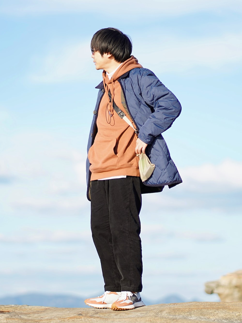 ブルー系のダウンジャケット/コート、ブラウン系のパーカー、ホワイト系のTシャツ/カットソーを着用したメンズの秋コーディネートの2枚目の写真