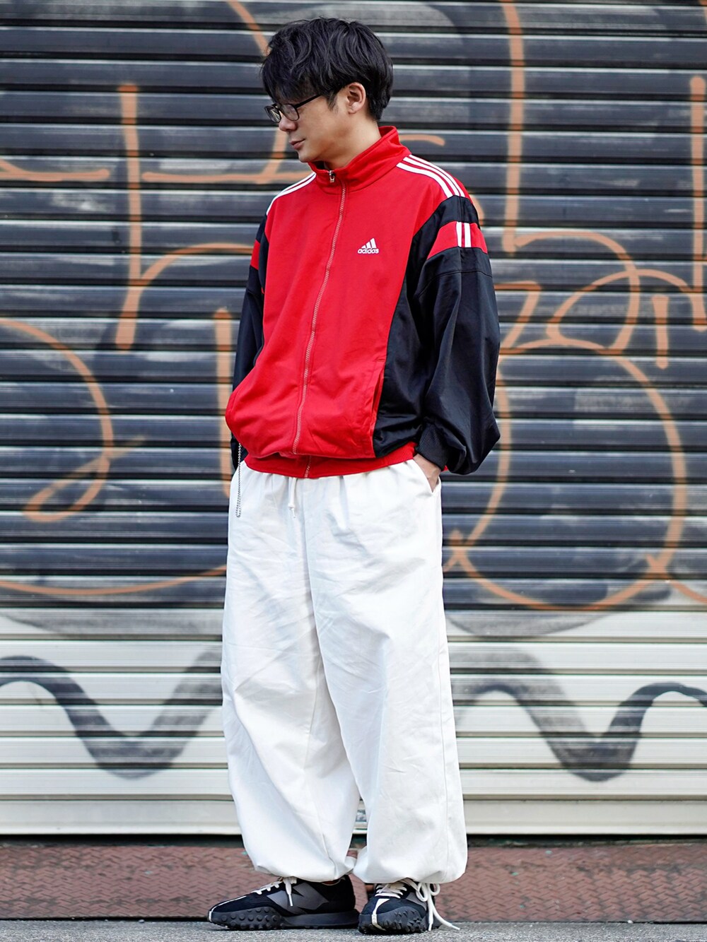 レッド系のナイロンジャケット、ホワイト系のその他パンツ、ブラック系のスニーカーを着用したメンズの春コーディネートの2枚目の写真