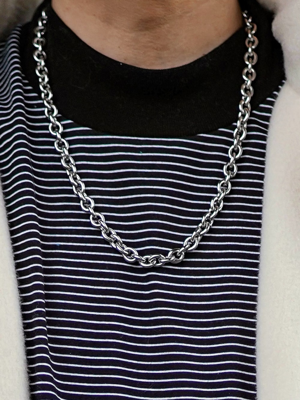 ホワイト系のブルゾン、ブラック系のTシャツ/カットソー、ブラック系のカーゴパンツを着用したメンズの冬コーディネートの2枚目の写真