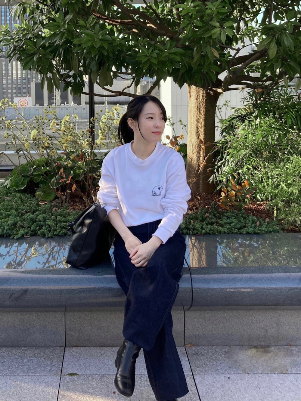 ホワイト系のスウェット、ブルー系のデニムパンツ、ブラック系のトートバッグを着用したレディースの秋コーディネートの2枚目の写真