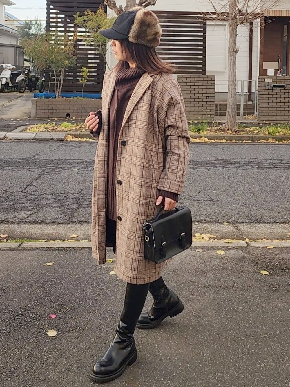 ブラウン系のチェスターコート、ブラウン系のニット/セーター、ブラック系のショルダーバッグを着用したレディースの冬コーディネートの3枚目の写真