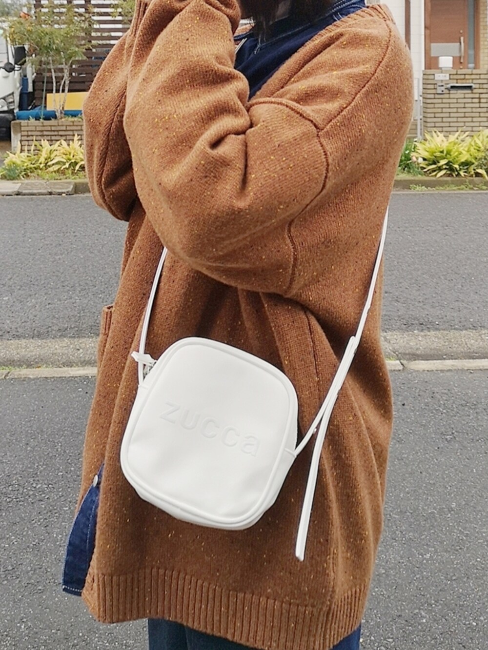 ホワイト系のショルダーバッグ、イエロー系のカーディガン/ボレロ、ブルー系のシャツ/ブラウスを着用したレディースの春コーディネートの2枚目の写真