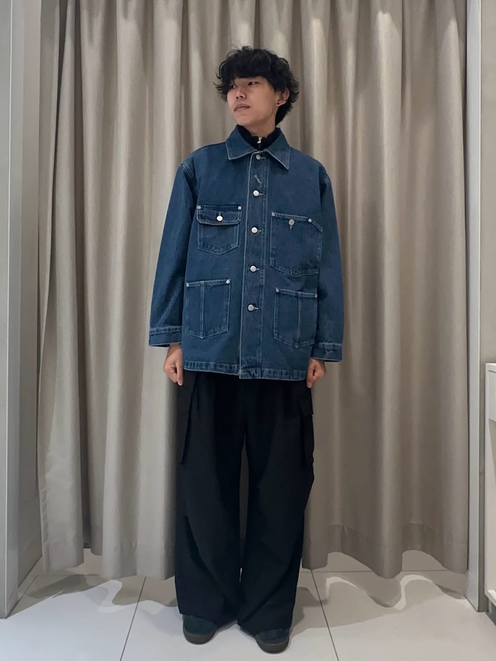 ブルー系のデニムジャケット、ブラック系のベスト、ブラック系のカーゴパンツを着用したメンズの秋コーディネートの2枚目の写真