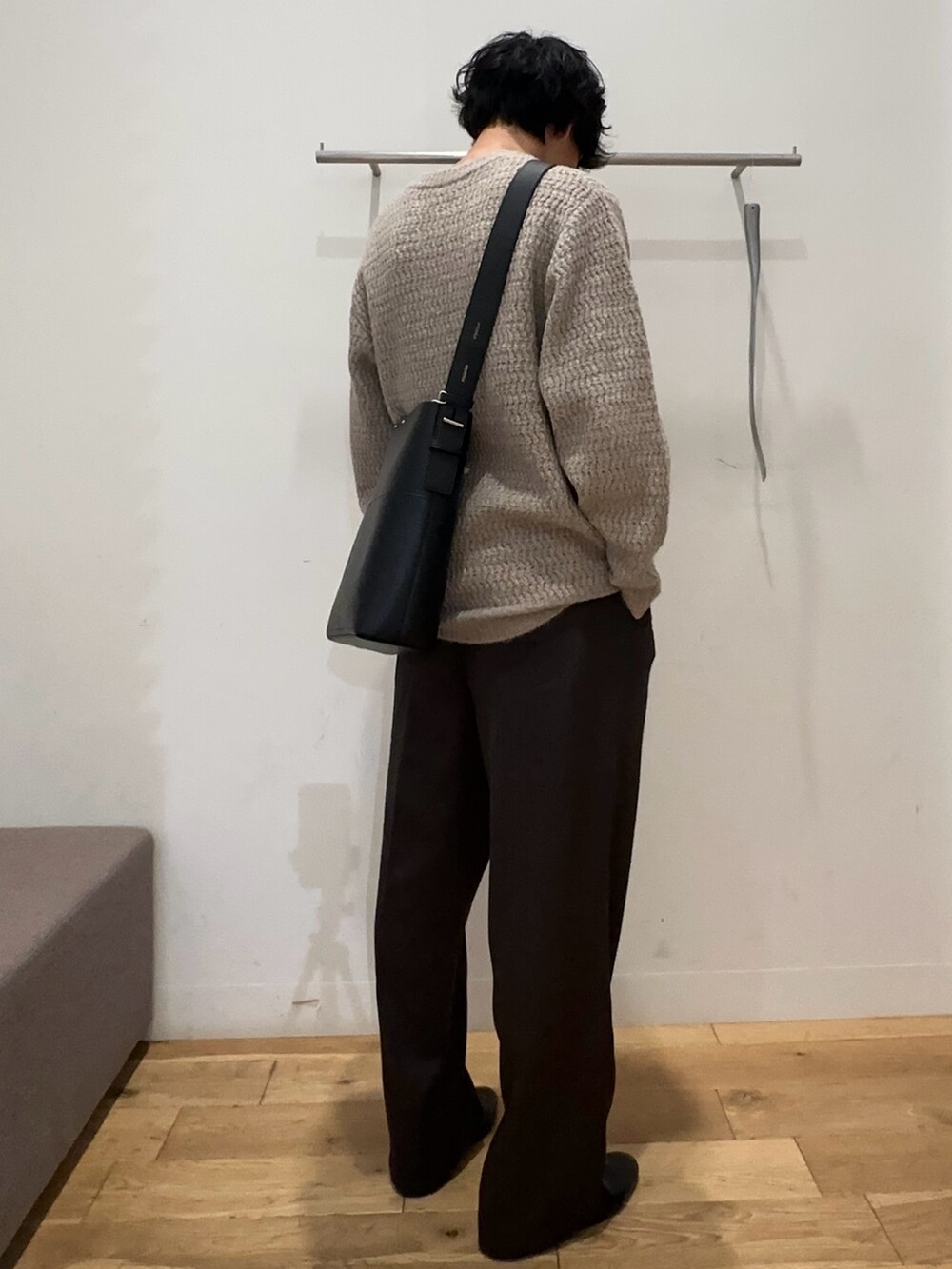 ブラック系のステンカラーコート、ホワイト系のニット/セーター、グレー系のその他パンツを着用したメンズの秋コーディネートの3枚目の写真