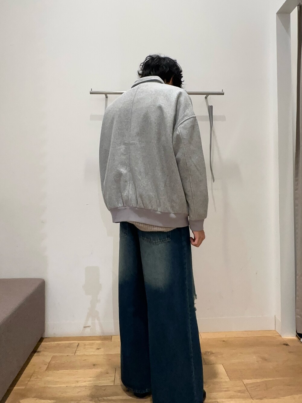 グレー系のブルゾン、ブルー系のデニムパンツ、ホワイト系のニット/セーターを着用したメンズの秋コーディネートの2枚目の写真