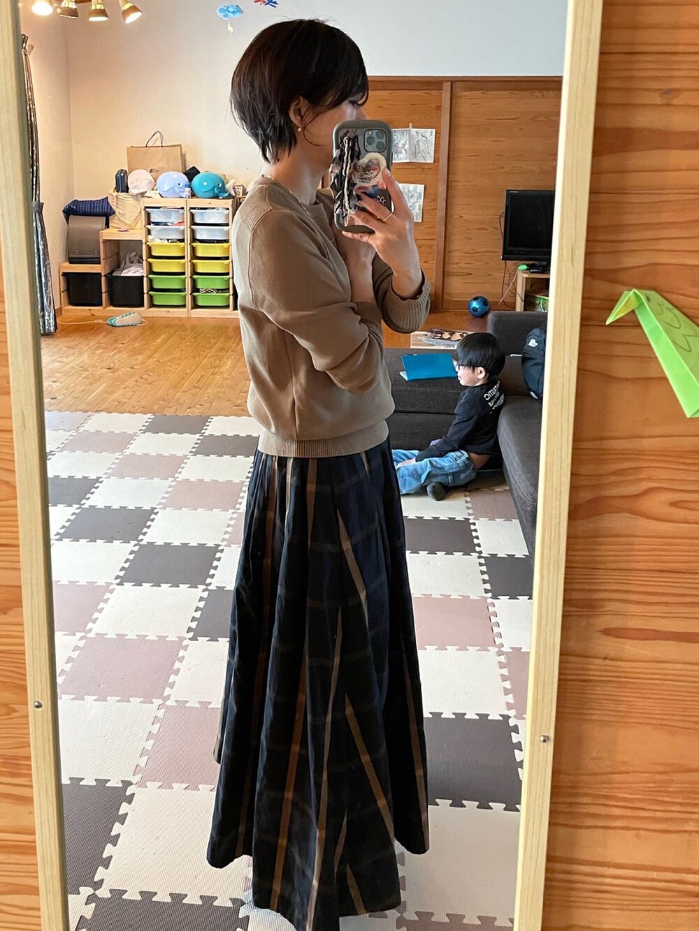 ベージュ系のニット/セーター、ブラック系のスカート、ゴールド系のネックレスを着用したレディースの春コーディネートの2枚目の写真