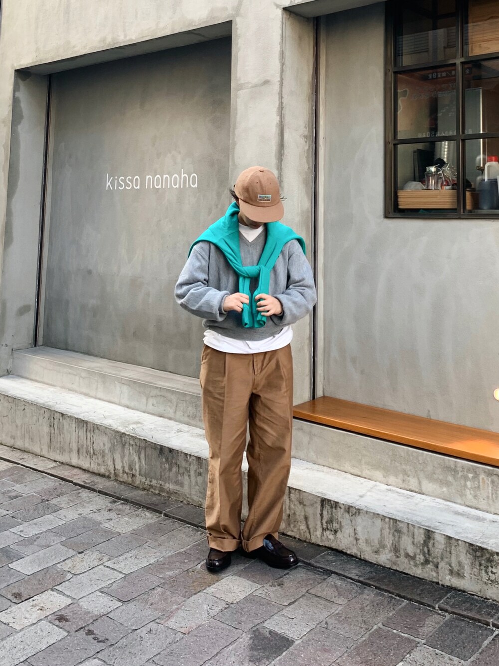 グレー系のニット/セーター、ブラウン系のチノパンツ、ブラウン系のローファーを着用したレディースの冬コーディネートの2枚目の写真