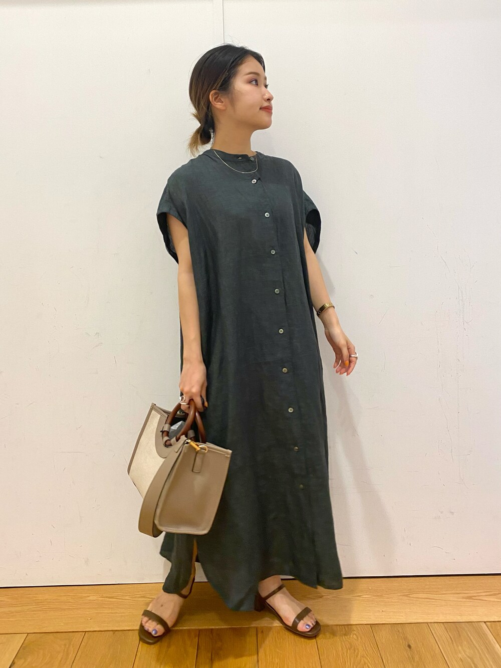 グレー系のトートバッグ、グリーン系のワンピース、ブラウン系のサンダルを着用したレディースの夏コーディネートの2枚目の写真